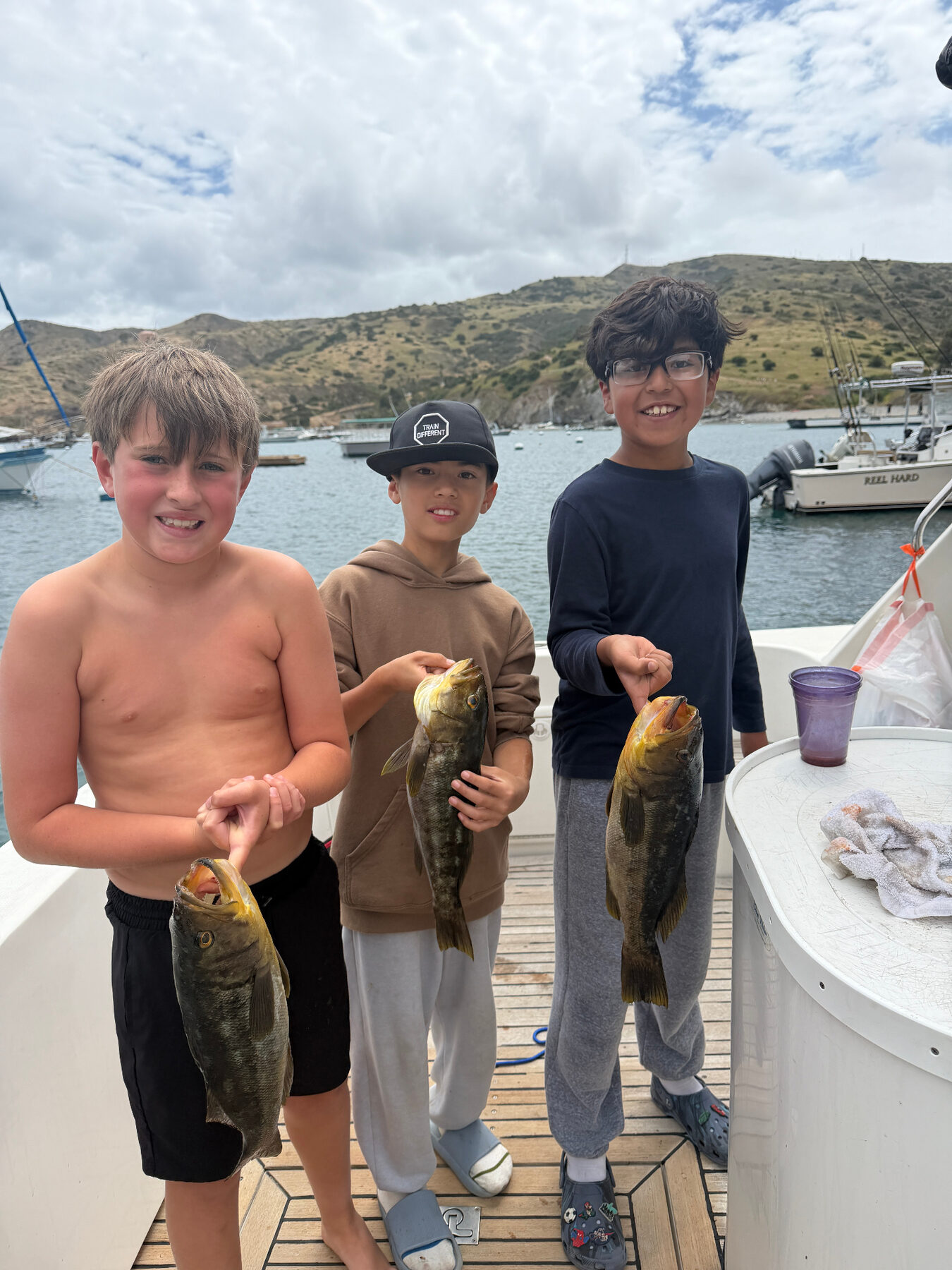 Three young anglers smiling with their catch aboard a fishing charter